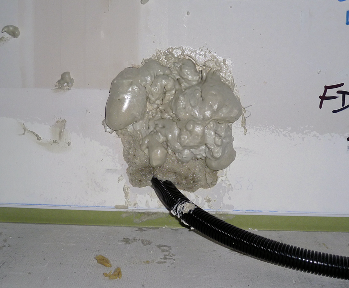 Expanded Polyurethane foam sealing cables through a gypsum wallboard partition.