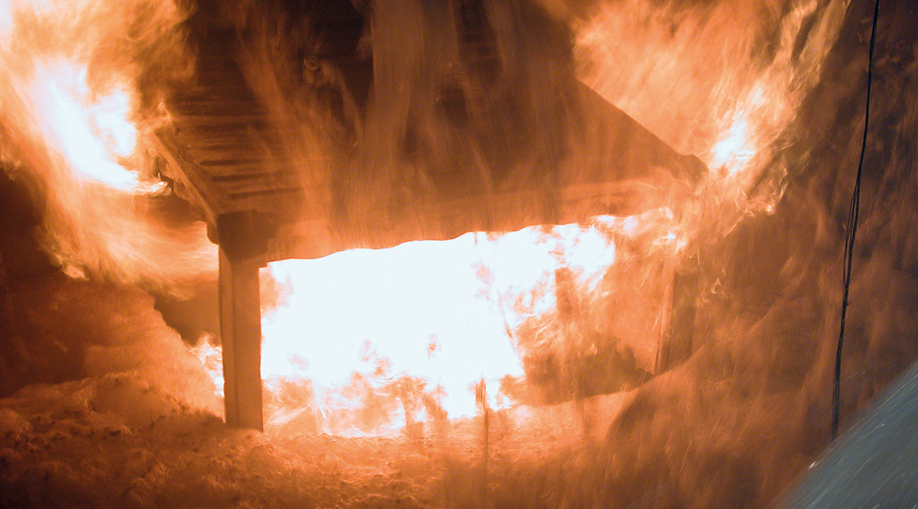 Figure 3 – The burning heptane pool when the foam has reached up to the edge of the locomotive’s apertures and started to flow in. At lower application rates, the foam did not manage to get into the locomotive, with the filling rate falling to zero when the foam had reached part-way up the locomotive.