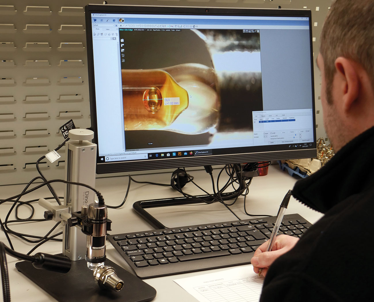 A member of the production team uses a microscope and software to determine the size of each bubble in the bulb.