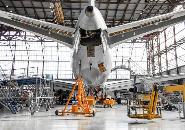 Aircraft in a hangar looking at an auxiliary power unit (APU).