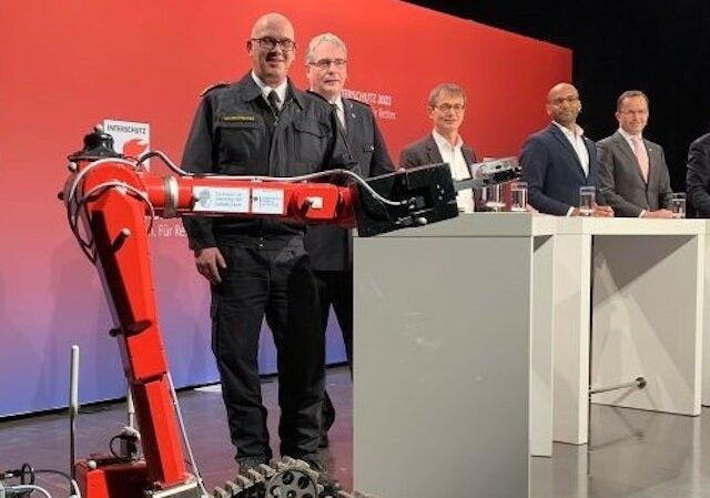 (from left to right): D2 Roboter, Dirk Aschenbrenner, President of the Association for the Promotion of German Fire Protection (vdfb); Karl-Heinz Banse, President of the German Fire Brigades Association (DFV); Dr. Bernd Scherer, Managing Director of VDMA Fire Fighting Technology; Onuora Ogbukagu, Corporate Spokesperson Deutsche Messe; Dr. Jochen Köckler, Chairman and CEO Deutsche Messe and Bernd Heinold, Senior Project Manager INTERSCHUTZ at Deutsche Messe. (INTERSCHUTZ)