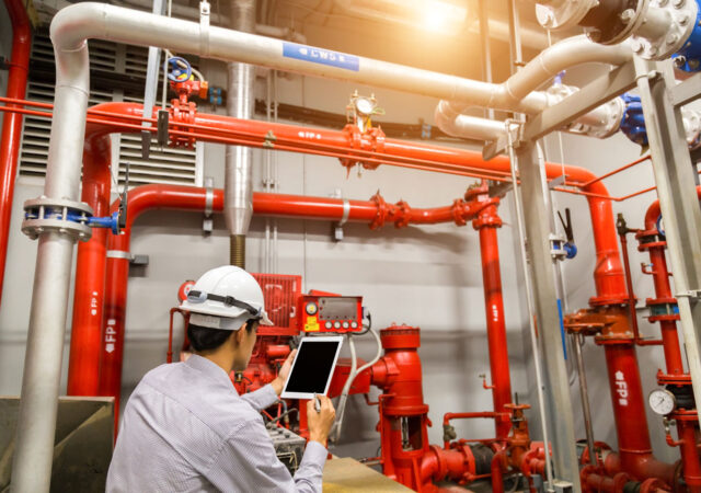 A safety auditor inspects site safety equipment using a tablet with fire-safety checklist software. (PlanRadar)